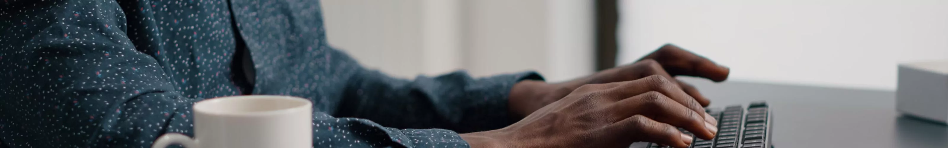 Close up of african american man hands typing on computer keyboard in living room, using internet online web communication from home office. Remote worker working from home