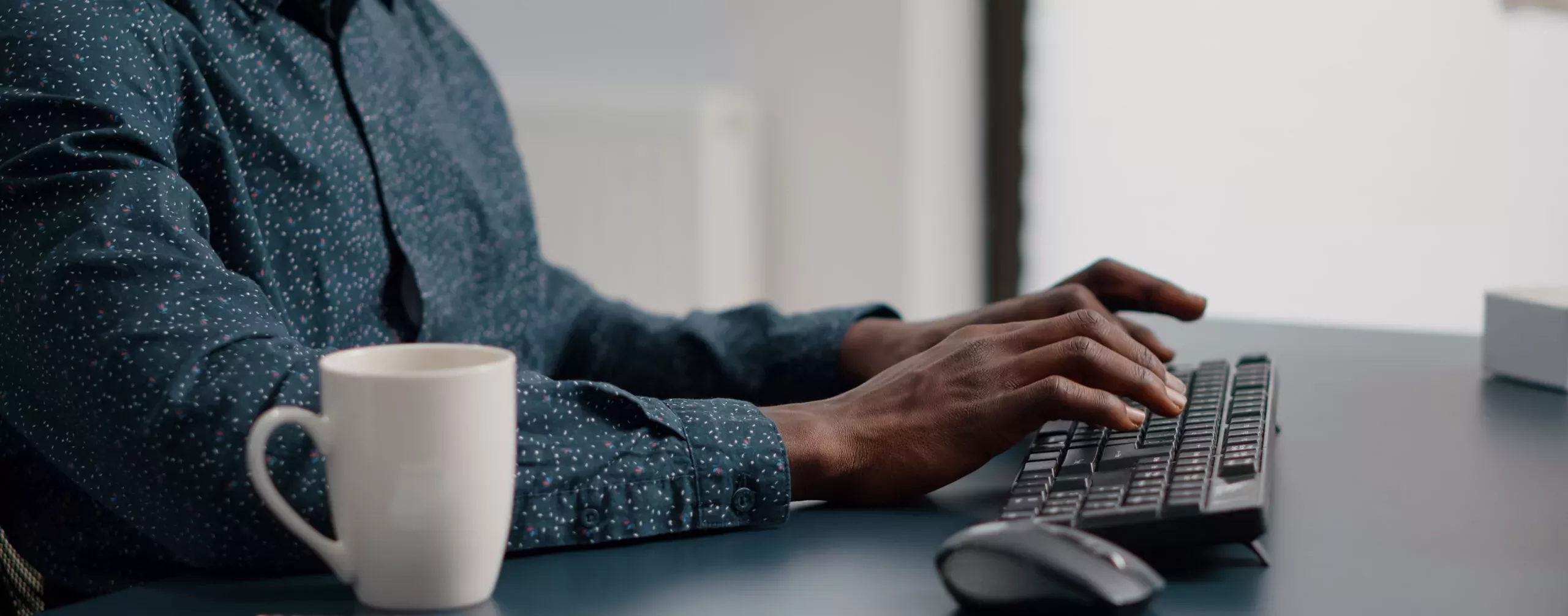 Close up of african american man hands typing on computer keyboard in living room, using internet online web communication from home office. Remote worker working from home